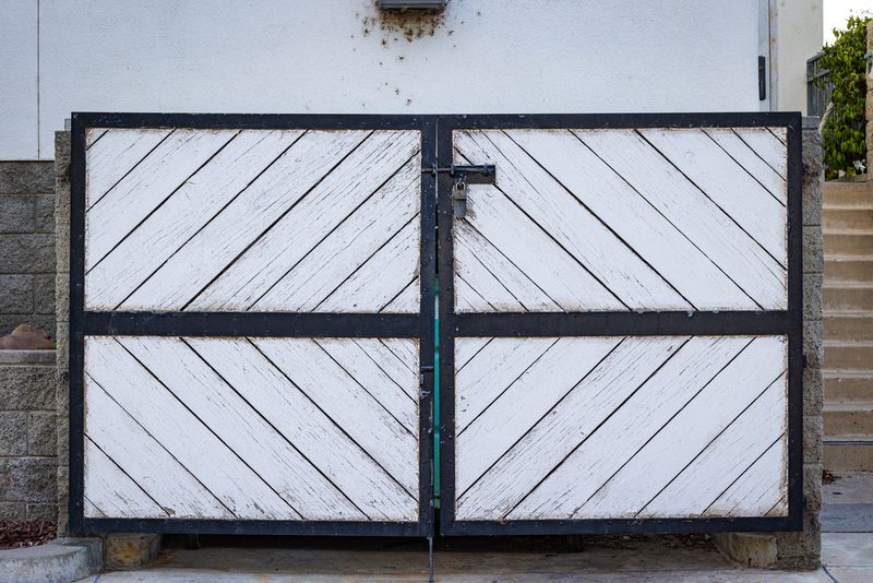 White wooden double gate with diagonal boards set in a black steel frame at a residential entrance